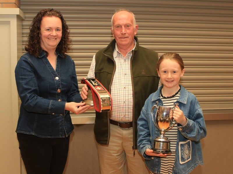 Geraldine McElduff (Countryside Services) with her daughter Molly presented the Perpetual Cow Bell winner, Bangor Six Road Ends Farmers' Union Perpetual Trophy to Joe Wilson for the Champion Simmental Female at Balmoral Show 2026 (Ballinalare Farm Nikita).