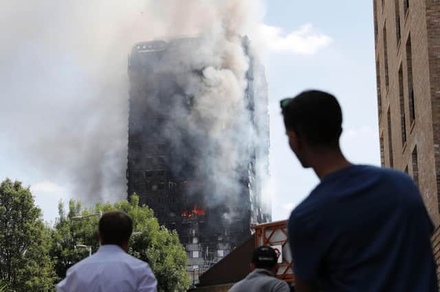 Pedestrians look up towards Grenfell Tower in London on June 14, 2017, as firefighters continue to control the fire that engulfed the building in the early hours of the morning. Picture: Adrian Denniss/AFP via Getty Images.