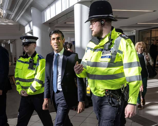 Prime Minister Rishi Sunak speaks with police officers as they walk in the corridors of the Swan Walk shopping centre during a visit in Horsham, West Sussex, on April 10. (Photo by RICHARD POHLE/POOL/AFP via Getty Images)