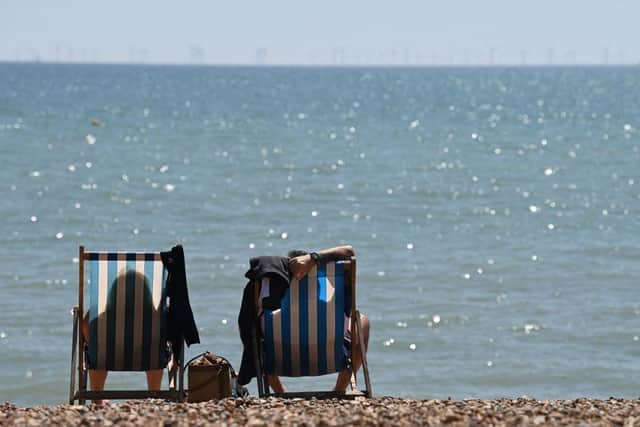 People sit in deckchairs looking out over the sea (Photo: GLYN KIRK/AFP via Getty Images)