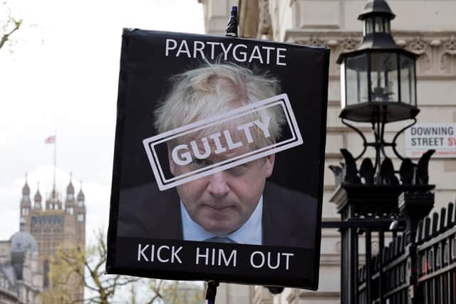 A demonstrator poses for a photograph holding a placard calling for the resignation of Boris Johnson  (Photo by TOLGA AKMEN/AFP via Getty Images)