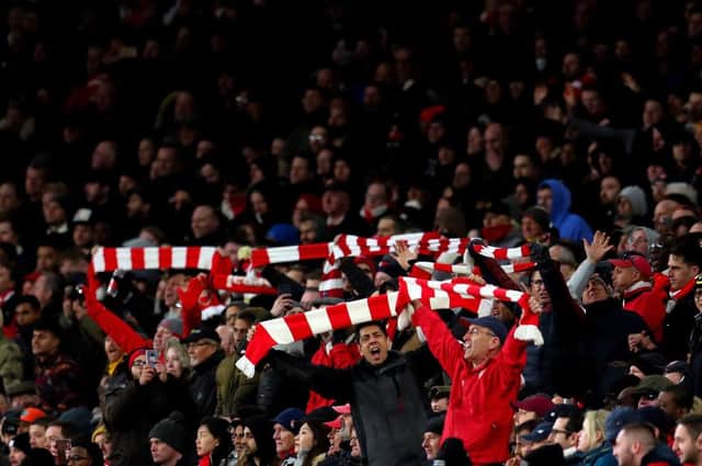 Fans of Arsenal hold up their scarves in support during the Premier League match between Arsenal FC and Manchester United in 2019.