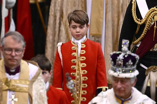 Page of Honour Prince George of Wales and Britain's King Charles III wearing the Imperial state Crown leave Westminster Abbey after the Coronation Ceremonies.