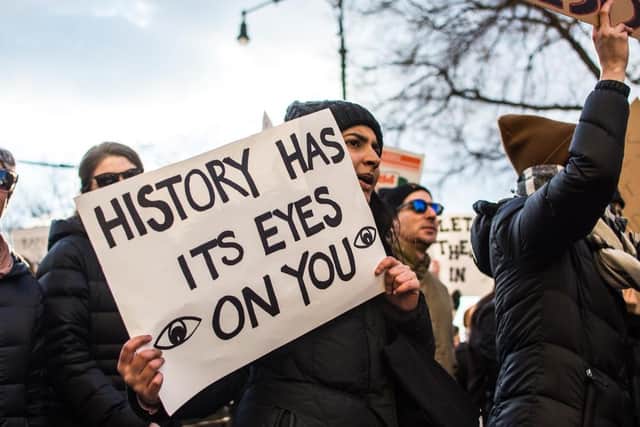 Protestor holding a sign which reads: “History has its eyes on you.” (Photo: Shutterstock/Jennifer M Mason) 
