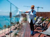 A hotel employee cleans a glass barrier on a terrace overlooking a beach (Photo: JOSEP LAGO/AFP via Getty Images)