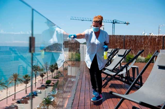 A hotel employee cleans a glass barrier on a terrace overlooking a beach (Photo: JOSEP LAGO/AFP via Getty Images)