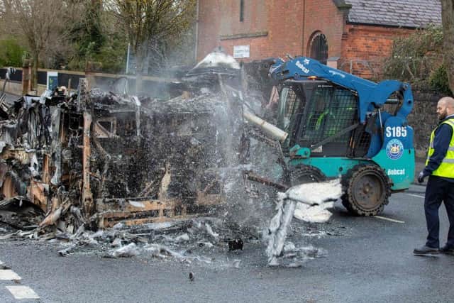 Belfast city council workers clear the remains of a burnt out bus on the loyalist Shankill Road in Belfast on April 8, 2021, after it was set on fire during a night of violence.