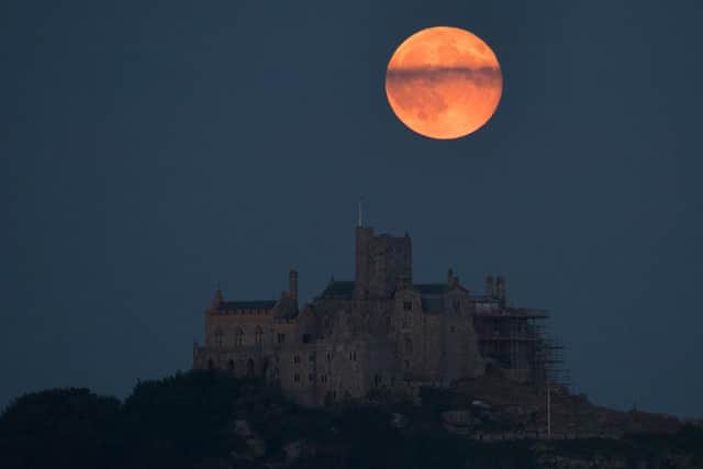 The full moon will be most visible in the UK on Thursday evening, appearing with a colourful glow much like this one which lit up the sky behind St Michael's Mount in Marazion near Penzance on June 28, 2018 (Picture: Getty Images)