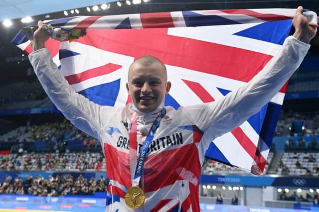Gold medallist Britain's Adam Peaty waves a Union flag after receiving his medal for winning the final of the men's 100m breaststroke swimming event during the Tokyo 2020 Olympic Games at the Tokyo Aquatics Centre in Tokyo on July 26, 2021. (Photo by Attila KISBENEDEK / AFP) (Photo by ATTILA KISBENEDEK/AFP via Getty Images)