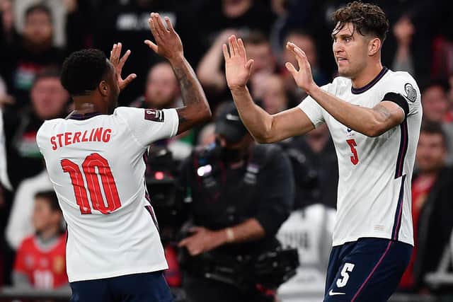 England's defender John Stones (R) celebrates with England's midfielder Raheem Sterling after scoring the equalising goal during the FIFA World Cup 2022 qualifying match between England and Hungary at Wembley Stadium in London on October 12, 2021.  (Photo by BEN STANSALL/AFP via Getty Images)