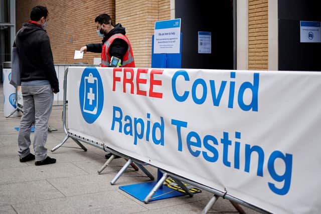 A worker hands out a leaflet to a person arriving at a rapid lateral flow Covid-19 testing centre (Photo by TOLGA AKMEN/AFP via Getty Images)