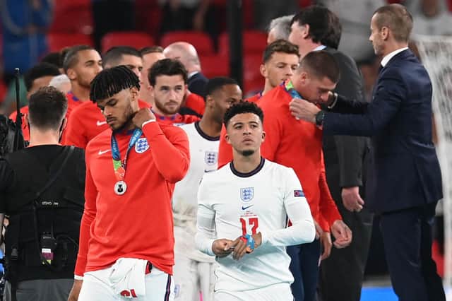 Tyrone Mings and Jadon Sancho take off their Euro 2020 runners up medals as England teammates collect their own after defeat to Italy. (Pic: Getty)
