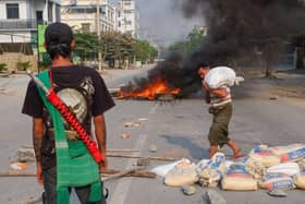 A man carries a sandbag to erect a barricade, as another burns in the distance, as security forces staged a crackdown on demonstrations against the military coup, in Mandalay on 22 March (Picture: Getty Images)