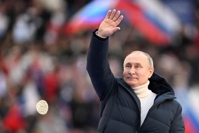 Russian President Vladimir Putin waves during a concert marking the eighth anniversary of Russia's annexation of Crimea at the Luzhniki stadium in Moscow. Photo by Ramil Sitdikov / POOL / AFP