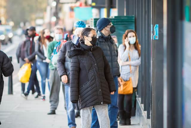 London, UK - 26 February, 2021 - Customers with face masks queueing outside the shop during the COVID-19 pandemic