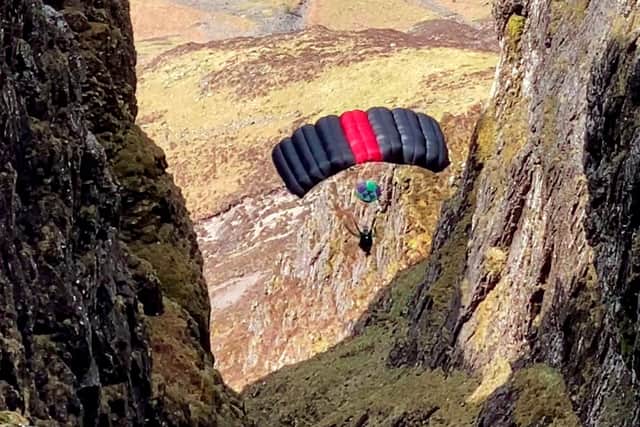 A person base jumps off a ridge at Aonach Eagach, Glen Coe, Scotland