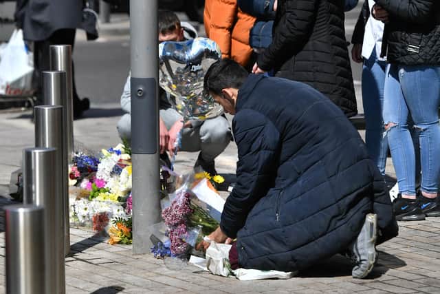 People place flowers at the scene in Barking Road, East Ham on Saturday, where 14-year-old Fares Maatou was killed (PA).