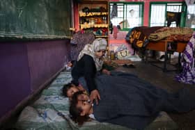 A Palestinian woman covers sleeping children with a blanket as they take refuge in a United nations school, in the Rafah refugee camp, in the southern of Gaza Strip.(Photo by MOHAMMED ABED/AFP via Getty Images)