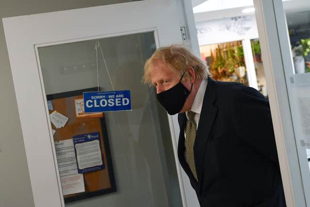 Prime Minister Boris Johnson walks past a sign reading 'we are closed' during a visit to Lemonheads Barber shop, Truro (Photo by Justin Tallis - WPA Pool/Getty Images)