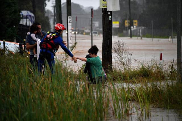 A rescue worker helps residents cross a flooded road (Photo: SAEED KHAN/AFP via Getty Images)