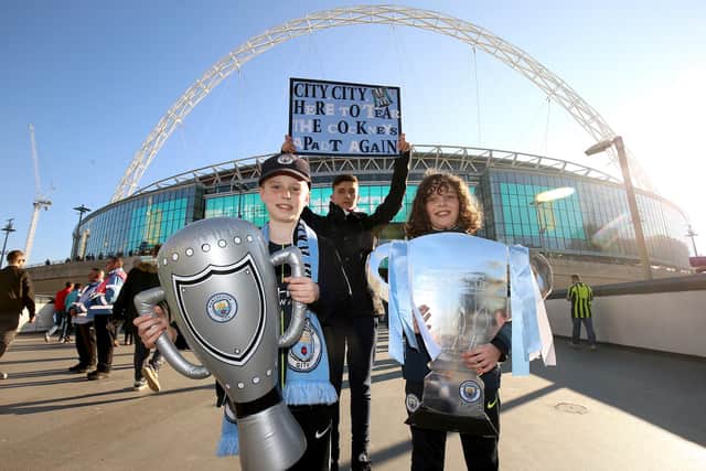 Manchester City fans hold up replicas of the Carabao Cup trophy prior to the beginning of the 2019 Carabao Cup Final at Wembley Stadium.