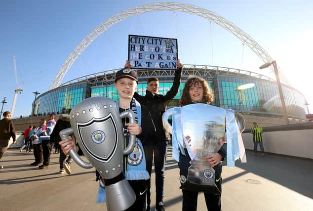 Manchester City fans hold up replicas of the Carabao Cup trophy prior to the beginning of the 2019 Carabao Cup Final at Wembley Stadium.