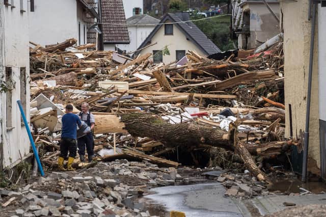 Two men try to secure goods from next to debris of houses destroyed by the floods in Schuld in western Germany (AFP/ Getty)