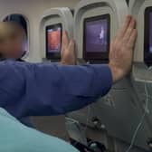 A plane passenger was caught holding this 'ridiculous' position to 'stop the seats in front of him reclining during eight-hour flight'.