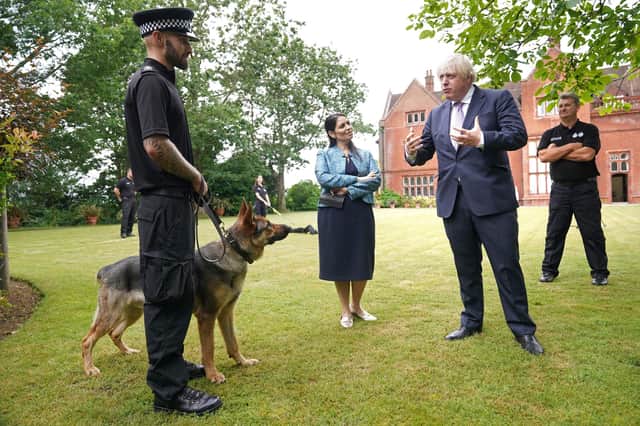Boris Johnson and Home Secretary Priti Patel speak to a police dog handler during a visit to Surrey Police headquarters in Guildford (Photo by Yui Mok / POOL / AFP)